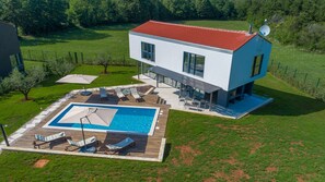 Une maison moderne à deux étages, dotée d’une piscine, d’un espace extérieur aménagé et d’une pelouse bien entretenue.