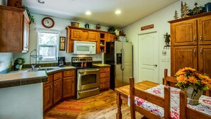A kitchen with wooden cabinets, a stainless steel refrigerator, a microwave, and a stove.