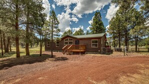 A rustic cabin with a wooden deck and a fenced yard.
