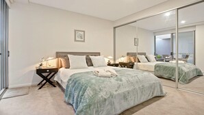 Een moderne slaapkamer met een groot bed, nachtkastjes en een spiegel.