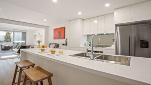 Een moderne keuken met een groot eiland, roestvrijstalen apparatuur en een eethoek met uitzicht.
