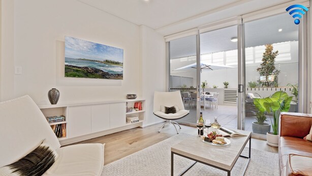Een moderne woonkamer met een groot raam, een eethoek met buitenmeubilair en uitzicht op de zee.