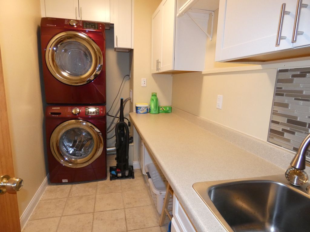 A compact kitchen with a double-washer unit, a sink, and a countertop with a few items.