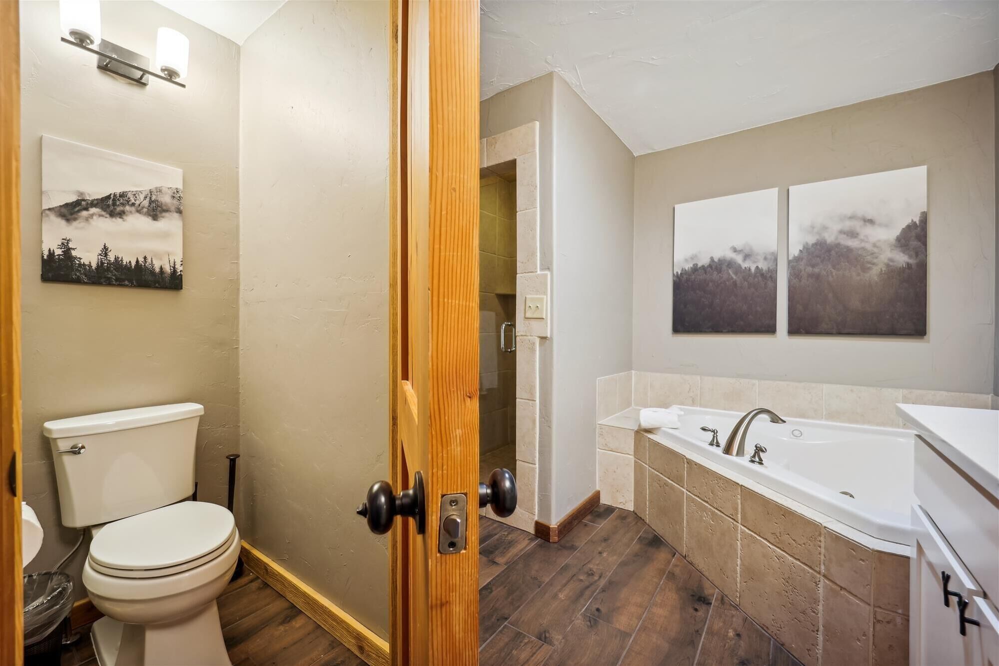 Un baño con inodoro, lavamanos y bañera. Hay dos lámparas de pared sobre el lavamanos.