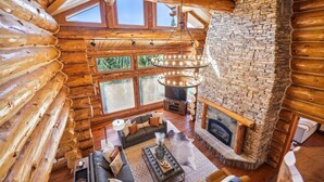 A log cabin interior with a stone fireplace, wooden beams, and a cozy seating area. - Baldy Mtn Log Ski Home, Game Room, Free Shuttle, Sleeps 12 (Breckenridge)