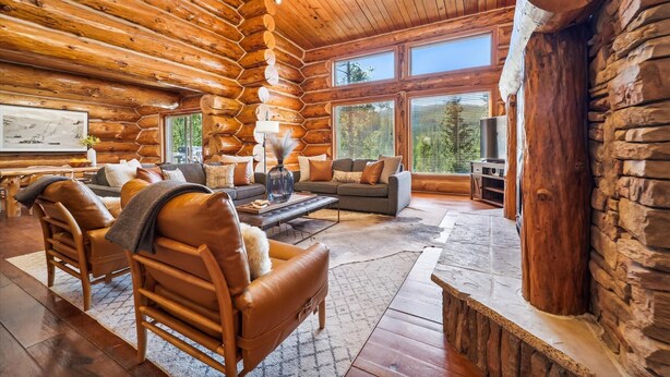 A log cabin interior with a fireplace, wooden furniture, and large windows. - Baldy Mtn Log Ski Home, Game Room, Free Shuttle, Sleeps 12 (Breckenridge)