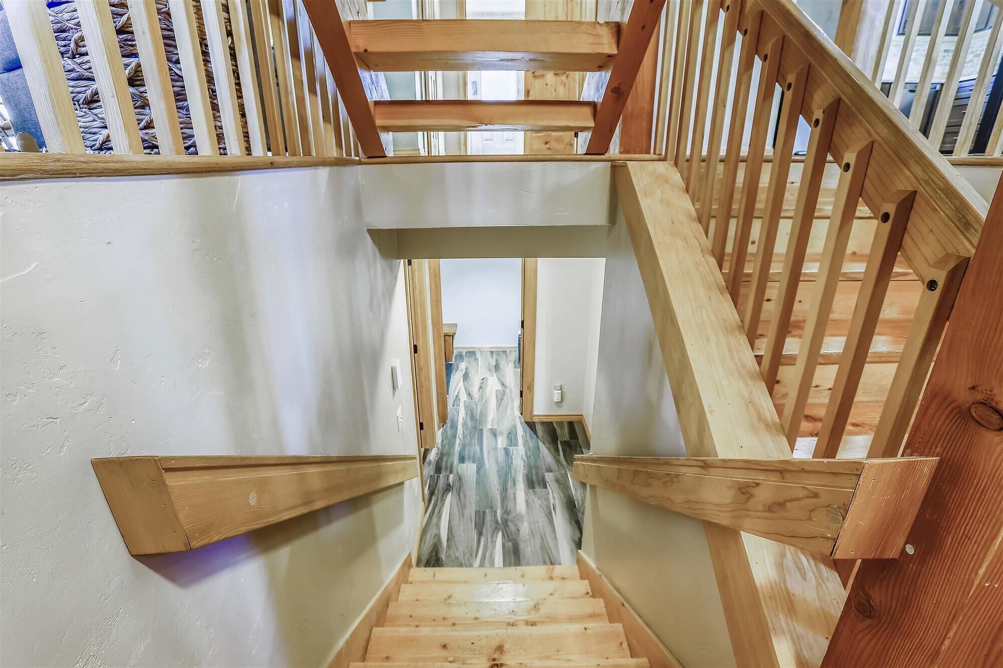 A wooden staircase with a handrail and a view of the interior space below.