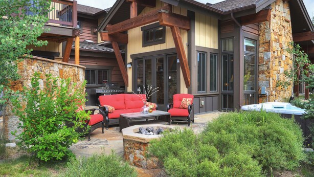Una casa moderna con fachada de piedra, una terraza y mobiliario exterior.
