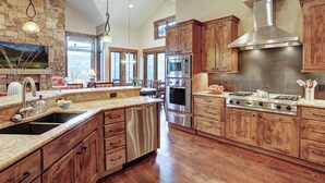 Una cocina amplia con armarios de madera, electrodomésticos de acero inoxidable y una isla grande con un lavamanos.