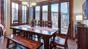 Un comedor con una mesa de madera, sillas y un florero con flores.