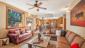 A spacious living room with a fireplace, leather sofas, a coffee table, and a dining area with wooden cabinets. - Spacious Breck Ski Home, Multiple Fireplaces, Gondola 2.1mi, Sleeps 10 (Breckenridge)