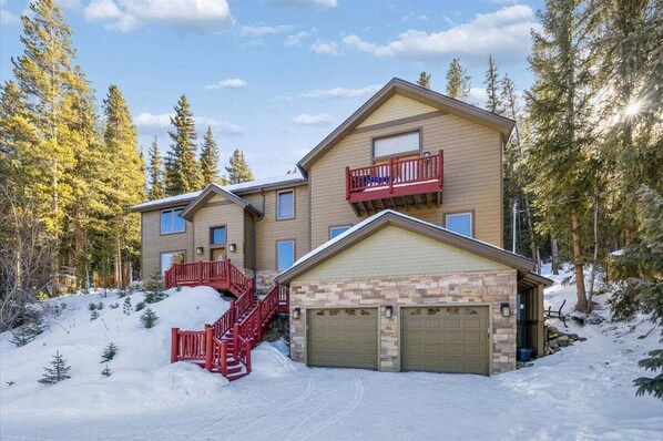 A two-story lodge with a red staircase, a garage, and a balcony. - High Point Lodge-Spacious Breck Ski Home, Multiple Fireplaces, Gondola 2.1mi, Sleeps 10 (Breckenridge)