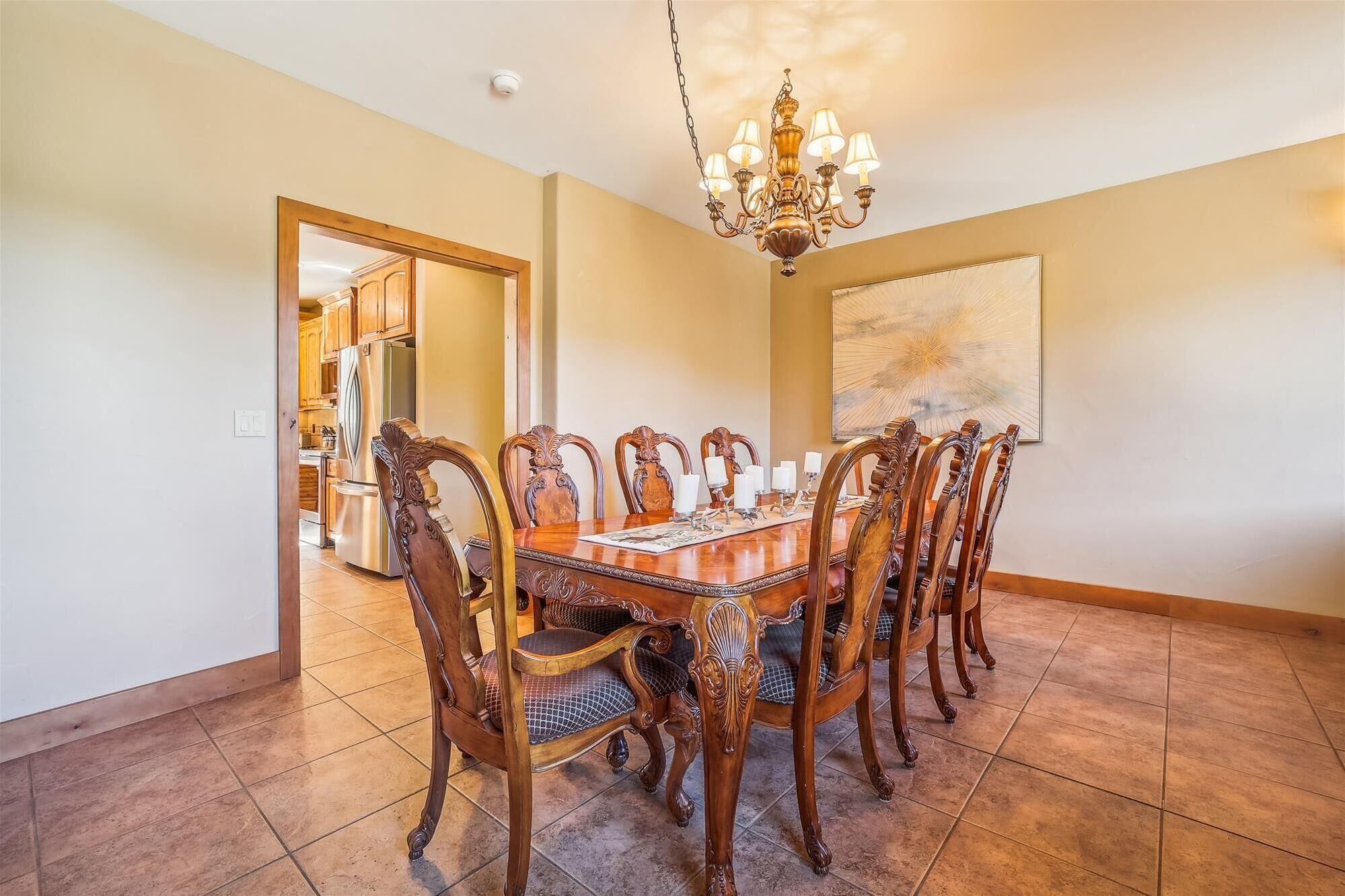Comedor con una gran mesa de madera, seis sillas y una araña.