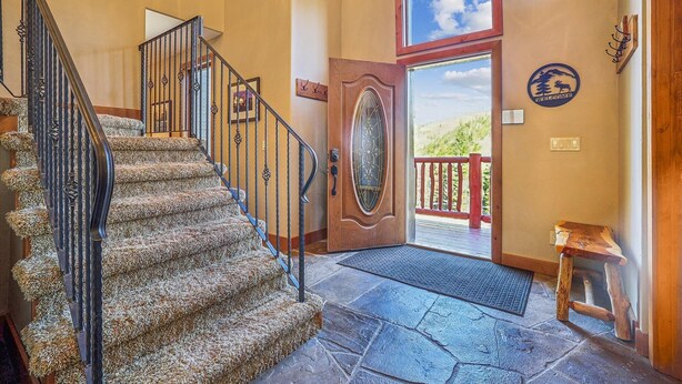 A staircase with a metal railing, a wooden door with a glass panel, and a stone floor. - Spacious Breck Ski Home, Multiple Fireplaces, Gondola 2.1mi, Sleeps 10 (Breckenridge)