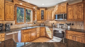 A spacious kitchen with wooden cabinets, a granite countertop, a built-in oven, and a large window offering a view of the outdoors. - Spacious Breck Ski Home, Multiple Fireplaces, Gondola 2.1mi, Sleeps 10 (Breckenridge)
