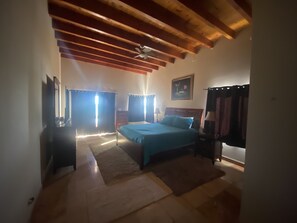 Ein Schlafzimmer mit einem Bett, einem Nachttisch, einer Lampe, einem Deckenventilator und einem Bild an der Wand.