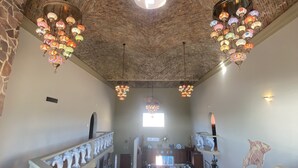 Eine großzügige Lobby mit hoher, gewölbter Ziegeldecke, verzierten Kronleuchtern und einer zentralen Treppe.