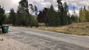 Un chemin de campagne bordé d’arbres, avec une cabane en bois au milieu.