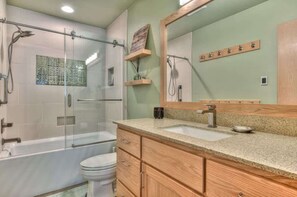 A modern bathroom with a glass-enclosed shower, a freestanding bathtub, a large mirror, and wooden cabinetry. - Luxurious home on the golf course (Sunriver)