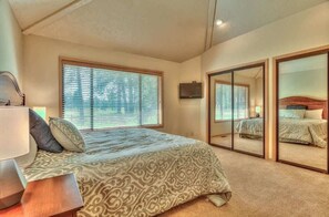 A bedroom with a bed, a bedside table, a lamp, a TV, and a sliding door closet. - Luxurious home on the golf course (Sunriver)