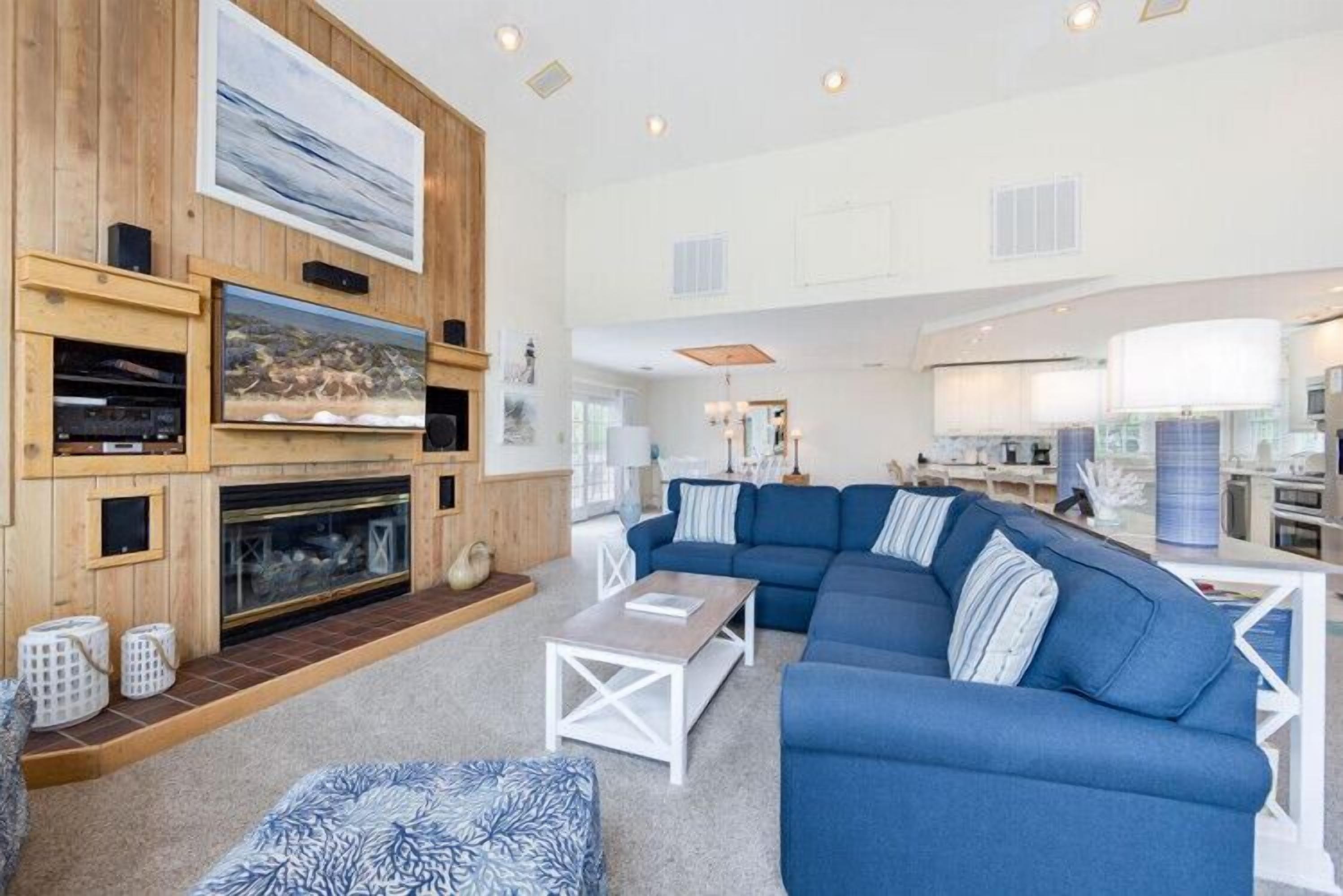 A modern living room with a fireplace, blue sofa, and a television.