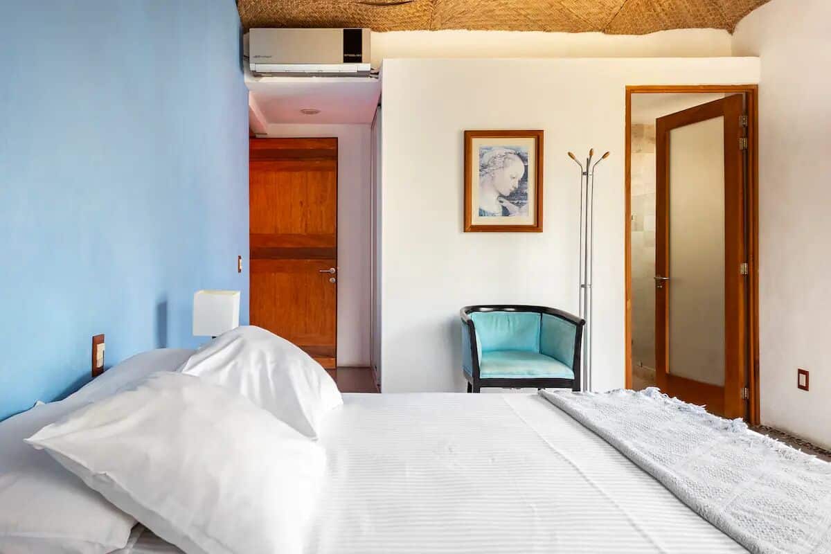 Ein Hotelzimmer mit Bett, einem Sessel, einem gerahmten Bild und einem Spiegel.