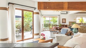 Un amplio salón con puerta de vidrio corredera que da a un patio exterior, ventilador de techo y techo de madera.