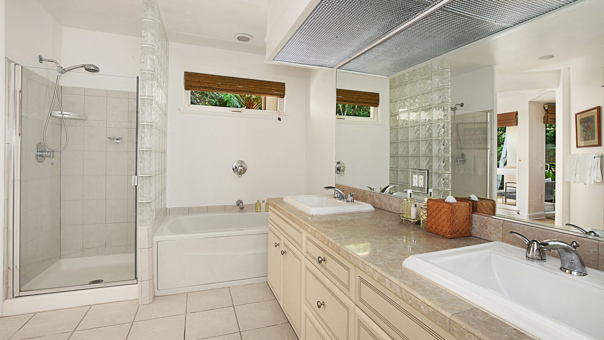 A modern bathroom with a glass-enclosed shower, a bathtub, and two sinks with vanity counters.