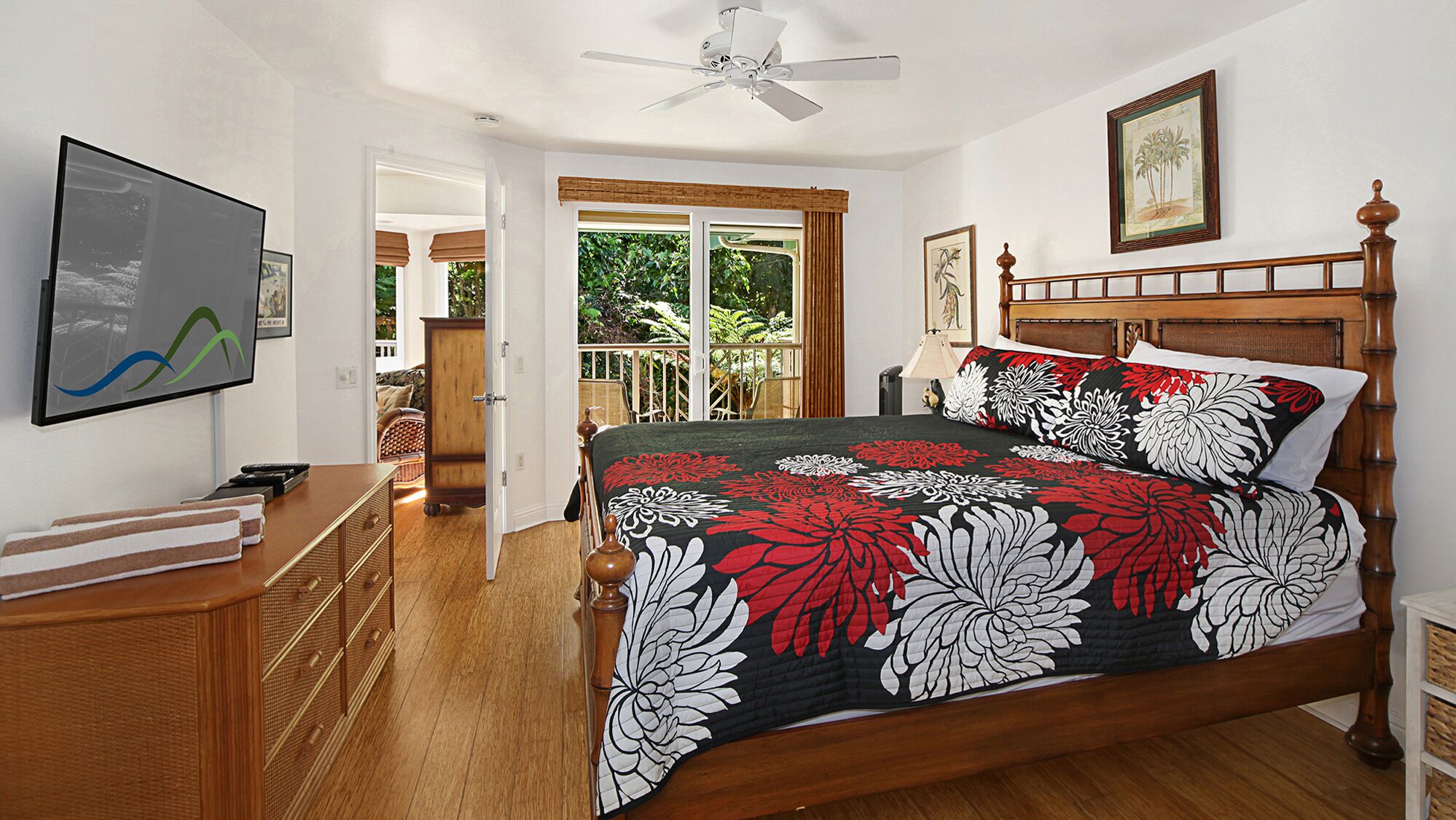 A bedroom with a wooden bed, a ceiling fan, a TV, and a view of the outdoors.