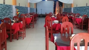 A dining area with red chairs and tables, white tablecloths, and blue drapes on the ceiling. - Hotel Cielo Azul (Cajamarca)