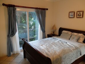 A bedroom with a bed, curtains, a nightstand, and two framed pictures on the wall.