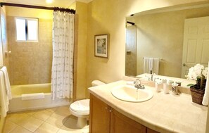 A bathroom with a bathtub, toilet, sink, and a large mirror.