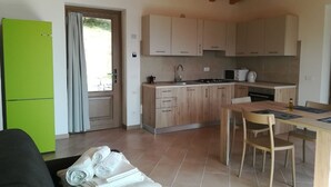 Una cocina compacta con armarios de madera, una mesa de comedor y un refrigerador verde.