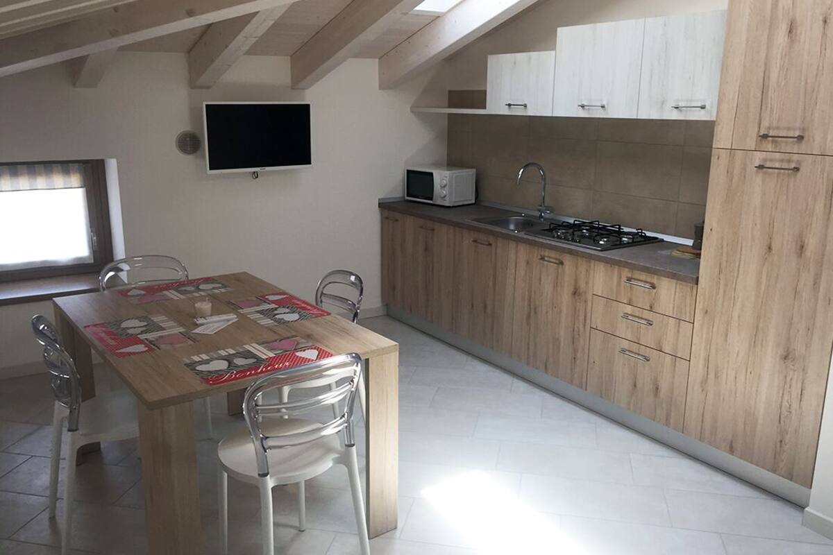 A compact kitchen with wooden cabinets, a microwave, and a gas stove.