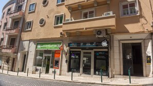 Um edifício com vários andares e uma loja no térreo, incluindo um caixa eletrônico e uma lavanderia automática.