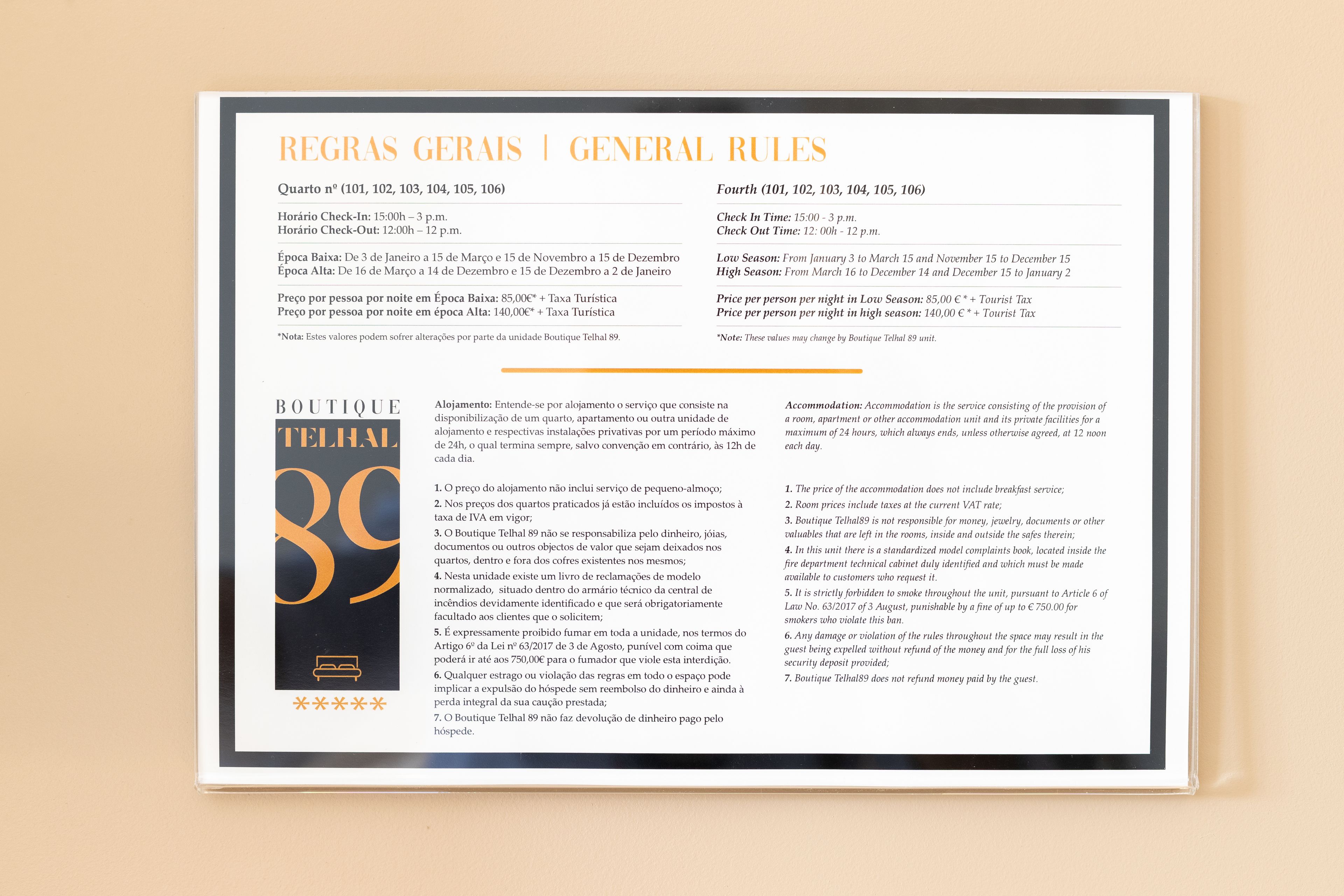A framed document titled 'REGRAS GERAIS | GENERAL RULES' with sections for 'Quartro nº (101, 102, 103, 104, 105, 106)' and 'Fourth (101, 102, 103, 104, 105, 106)'. It includes check-in and check-out times, low and high season prices, and a list of rules for Boutique Telhal 89.