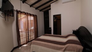 Ein Schlafzimmer mit einem Bett, einem an der Wand montierten Fernseher und einer Klimaanlage.