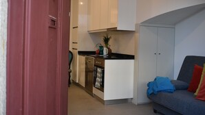 A compact kitchen with white cabinets, a built-in oven, and a small countertop.