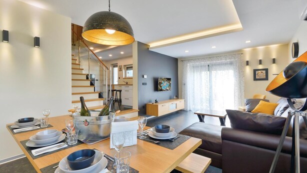 Een moderne woonkamer met een eethoek, een bank, een salontafel en een televisie.