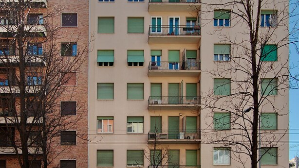 A multi-story residential building with balconies, a gated entrance, and a visible parking area. - Apartment Near Corso Buenos Aires, Milano Central (Milan)
