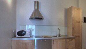 A modern kitchen with a microwave, a sink, and wooden cabinets. - Apartment Near Corso Buenos Aires, Milano Central (Milan)