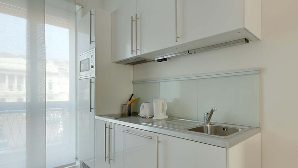 Een moderne keuken met witte kastjes, een roestvrijstalen spoelbak en een raam met uitzicht op een stadsgezicht.