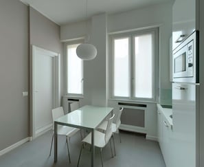 Una cocina moderna con una mesa y sillas blancas, ventanas grandes y electrodomésticos integrados.