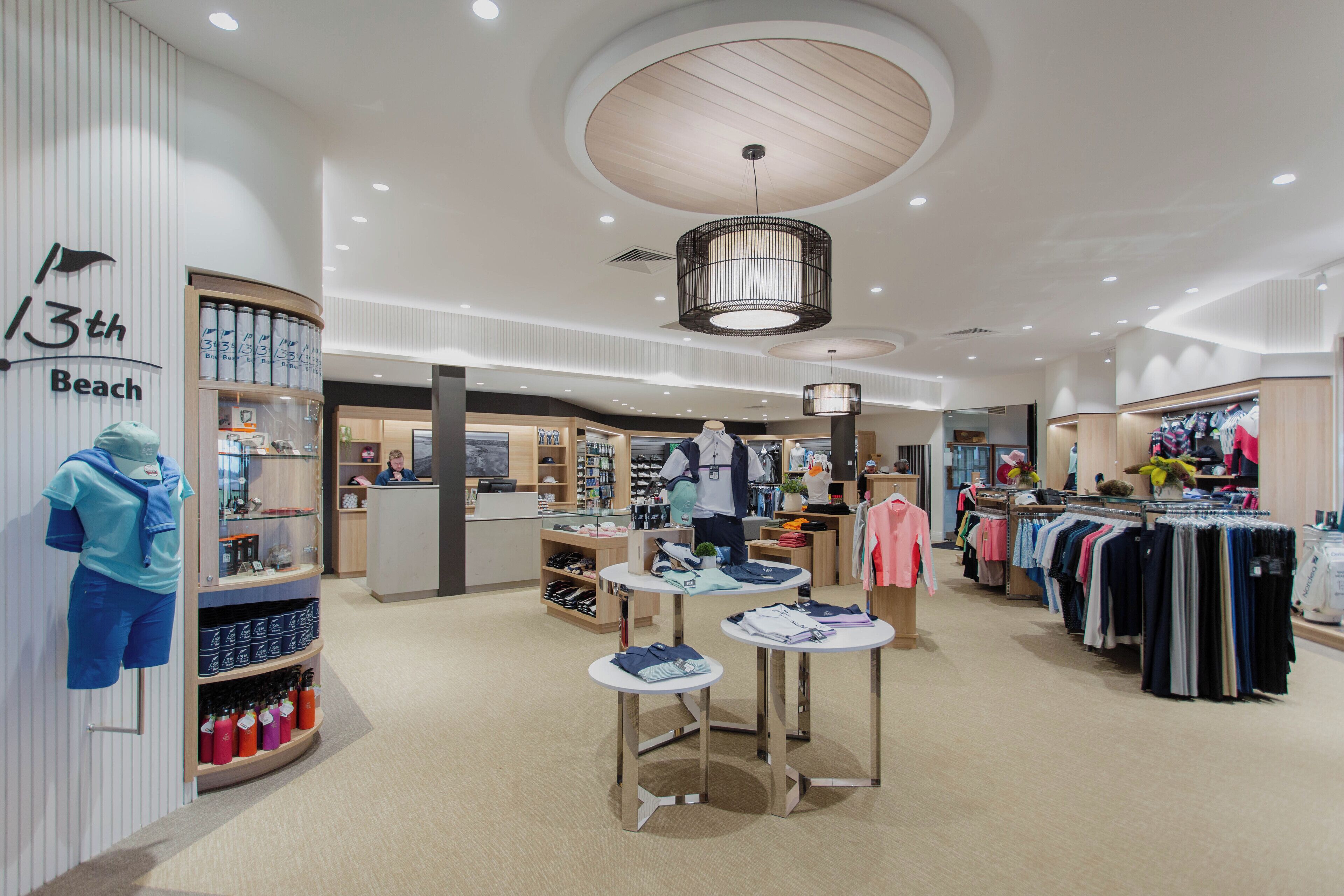 Una tienda moderna con exhibiciones de ropa, una zona de recepción y un diseño de techo de madera.