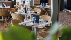 Un restaurante con sillas y mesas de mimbre dispuestas para comer, con vistas al exterior.