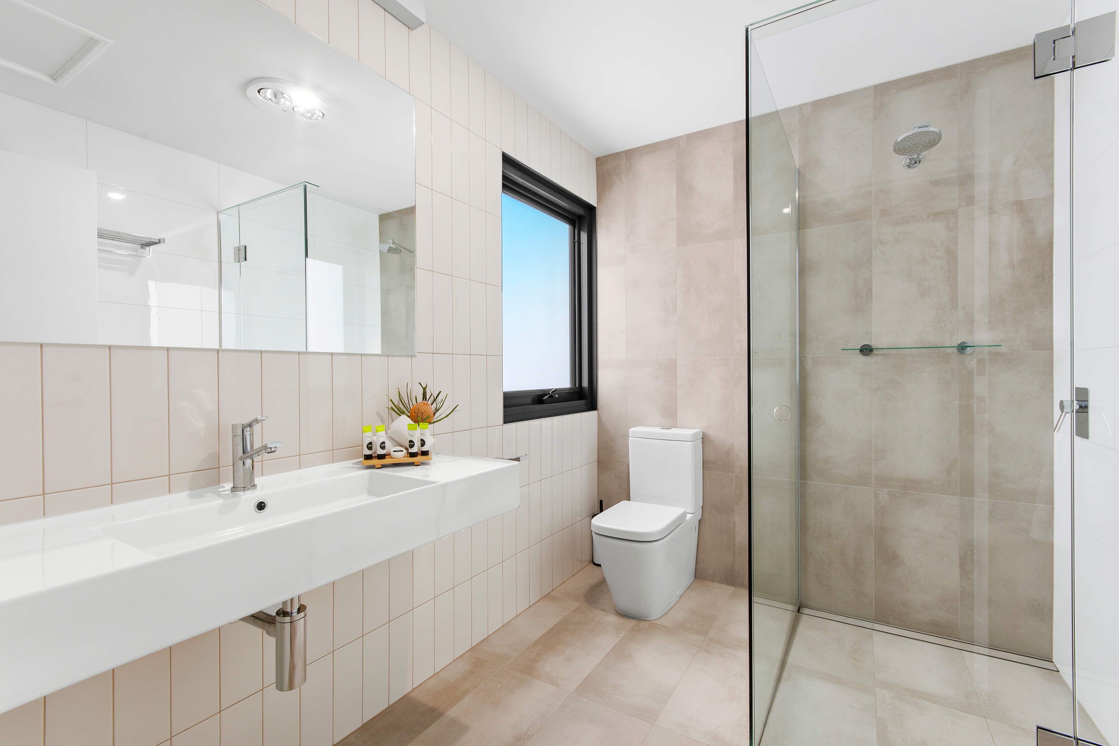 A modern bathroom with a glass-enclosed shower, a white sink, and a toilet.