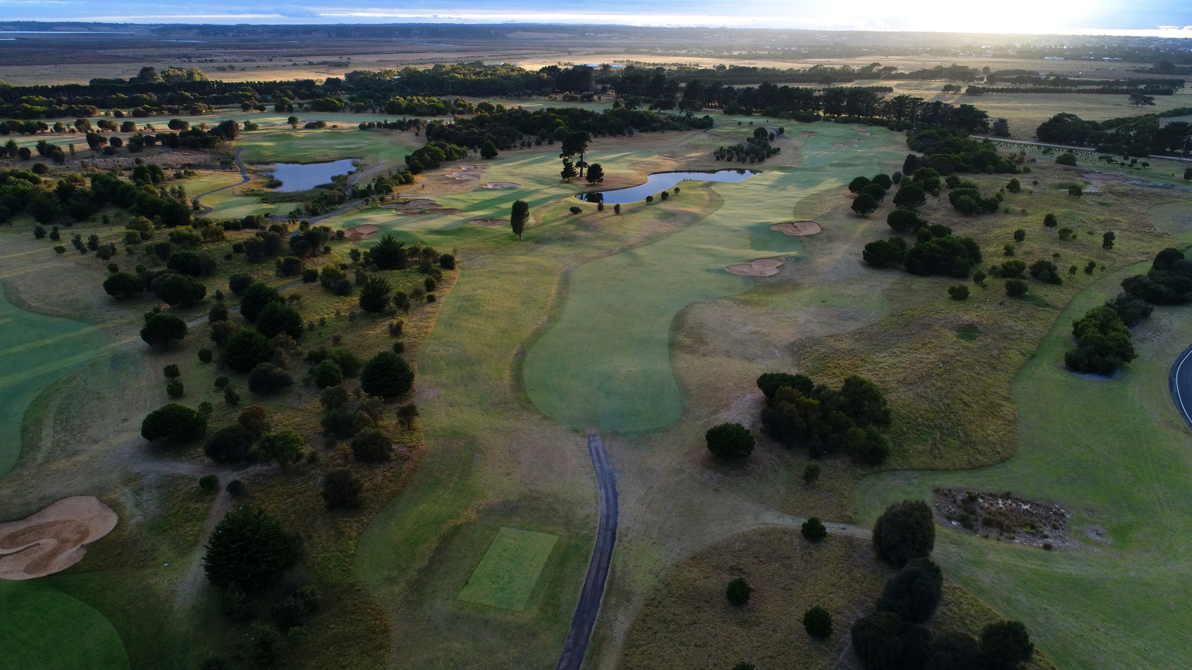Vue aérienne d’un parcours de golf comportant plusieurs trous, des obstacles d’eau et des arbres dispersés.