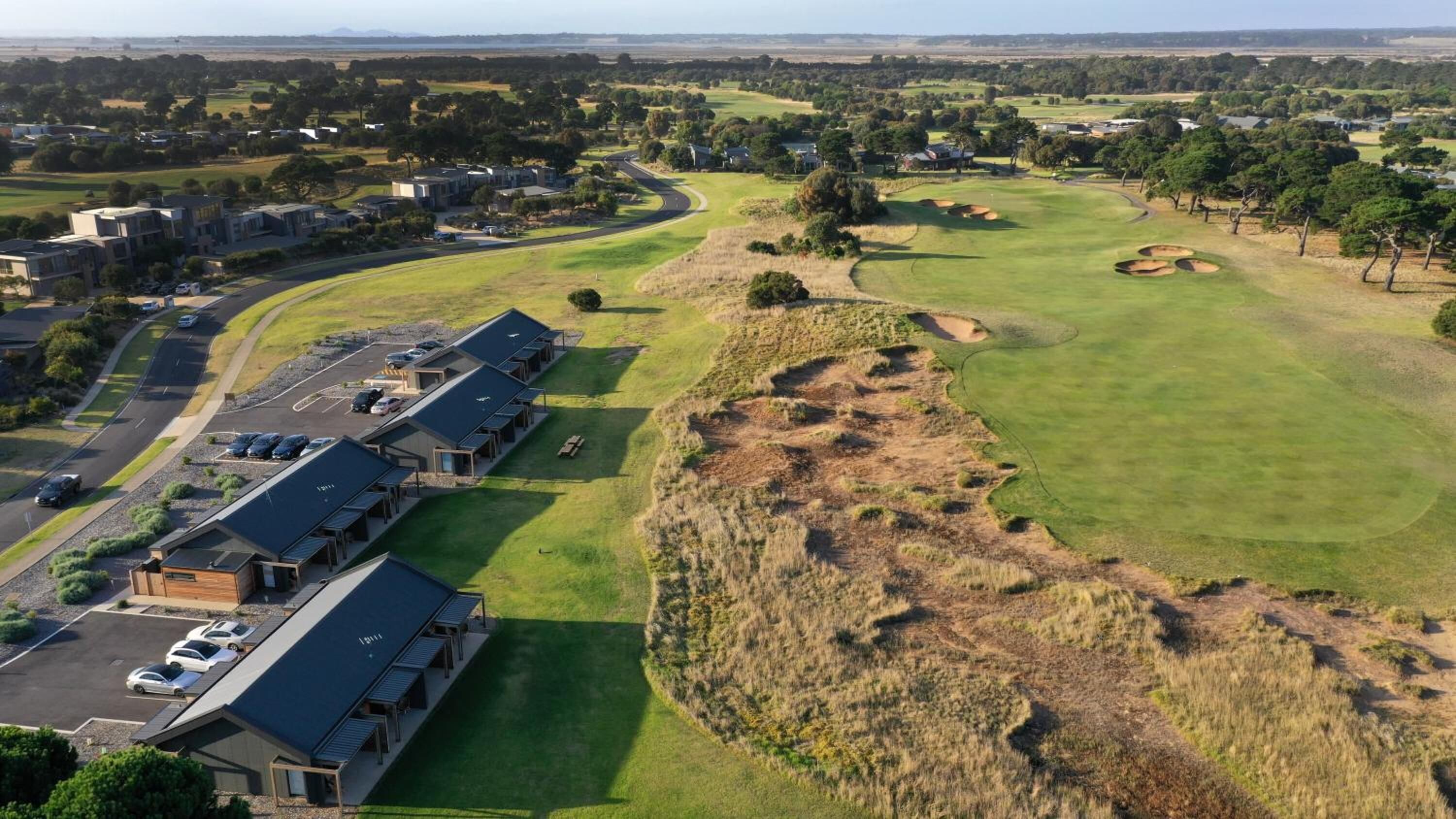 A golf course with bunkers and a clubhouse with multiple units.