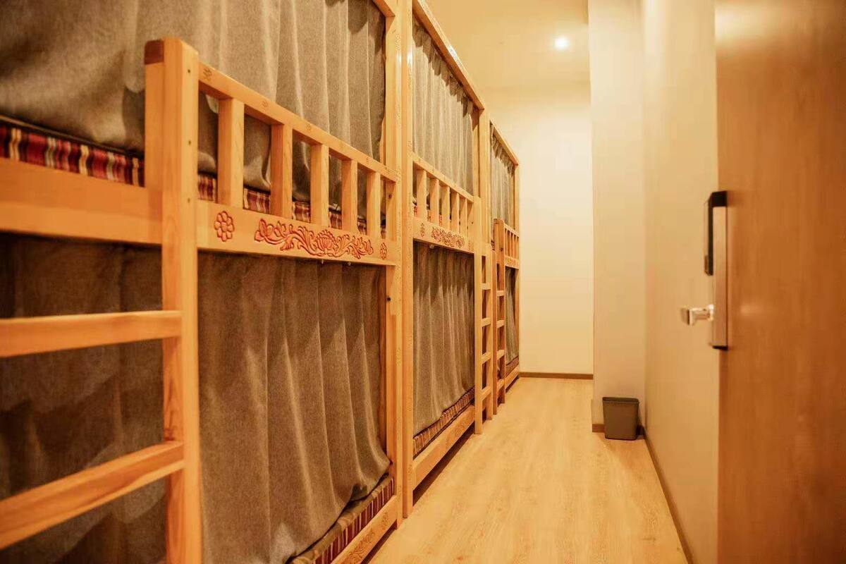 Um corredor com beliches, grades de madeira e uma porta com maçaneta.