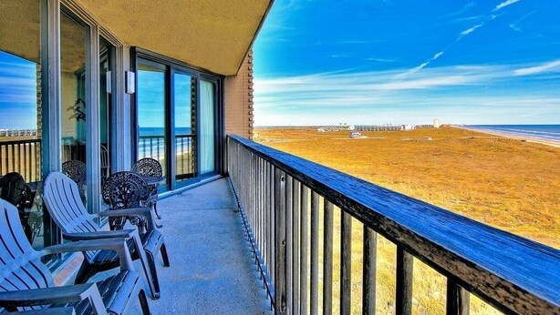 Un balcón con vistas a la playa, que incluye una zona de estar con sillas y una mesa.